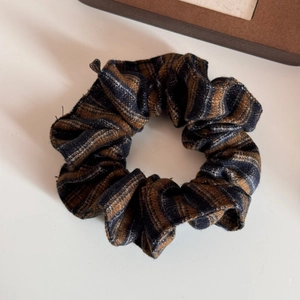 Detail of vintage plaid scrunchie with thick wool-blend texture in brown and navy