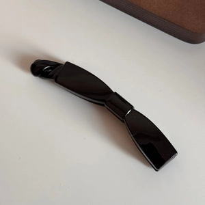Détail de la pince banane noire minimaliste en résine avec finition brillante
