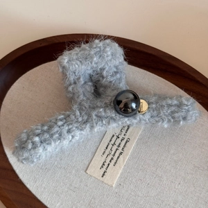 Detail view of plush faux fur hair claw with large black pearl and gold accent