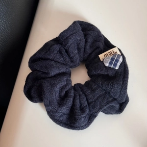 Dettaglio dell'elastico in maglia intrecciata blu scuro con etichetta e cuore a quadri