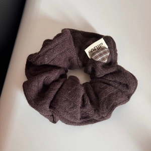 Dettaglio della fascia in maglia marrone cioccolato con etichetta vintage a cuore