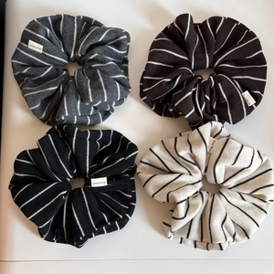 Détails de quatre chouchous rayés en tricot dans les tons gris, marron, noir et crème