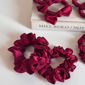 Detailed view of dark red satin scrunchies with smooth texture and elegant bow design