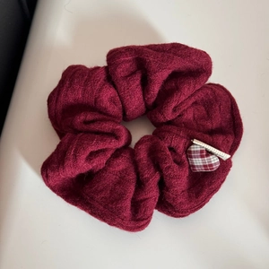 Dettaglio fascia per capelli in maglia bordeaux con ciondolo a cuore a scacchi