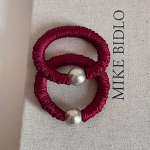 Close-up of festive red satin scrunchies with metallic silver beads on a textured book