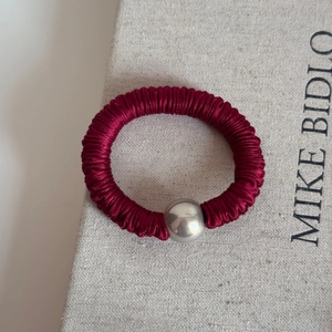 Close-up of deep red silk hair scrunchie with large silver metallic bead ornament