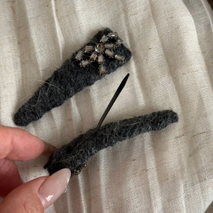 Détail de pinces à cheveux en feutre gris avec nœud en strass et clip en métal noir