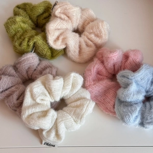 Dettaglio di sei elastici per capelli in maglia soffice in colori pastello su bianco