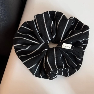 Détail d'un chouchou à rayures noires et blanches avec une étiquette Hand Made