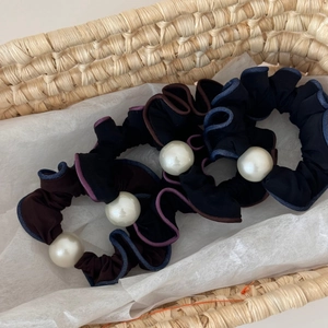 Close-up of three vintage pearl hair ties with contrast edges in a woven basket