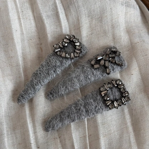 Vue détaillée de trois barrettes en tricot gris avec strass en forme de cœur et de nœud