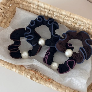 Detail of four ruffle hair scrunchies with white pearls in a woven basket display