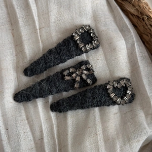 Détail de trois barrettes en peluche grise avec strass en forme de cœur, nœud et carré
