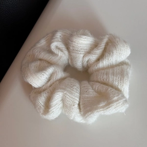 Dettaglio di uno scrunchie in maglia bianca con morbida trama di lana e trama fitta