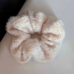 Dettaglio dell'elastico per capelli in peluche crema con trama in maglia di pelliccia