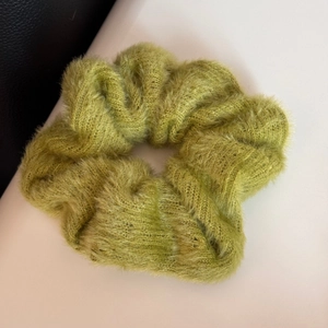 Dettaglio di un elastico per capelli in maglia verde oliva con morbida trama vellutata