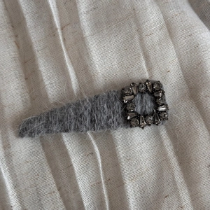 Vue macro d'une barrette à cheveux en peluche grise avec boucle en cristal rectangulaire