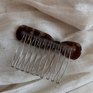Détail du peigne à cheveux en acétate écaille avec dents en métal argenté sur lin beige