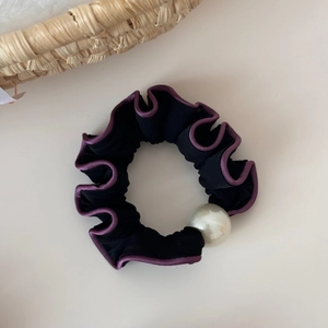 Detail of black ruffled hair scrunchie with purple edge and a large white pearl bead