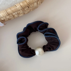 Detail of dark brown scrunchie with blue piping and a large elegant faux pearl accent