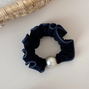 Detail of black fabric hair tie with blue denim edges and a large white pearl accent