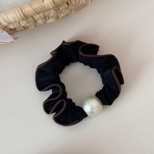 Detail of a vintage black ruffled hair scrunchie with a large white pearl bead accent