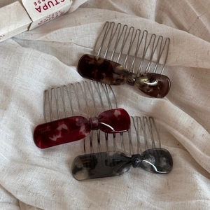 Trois peignes à cheveux avec nœuds en acétate écaille et marbre sur tissu en lin