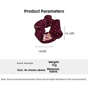 Detailed view of burgundy polka dot scrunchie with fabric label and 14cm size specification