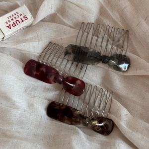 Détail d'un lot de trois peignes à cheveux en forme de nœud, gris, bordeaux et écaille