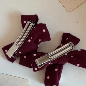 Detail of burgundy polka dot velvet bow hair clips with silver metal duckbill attachment