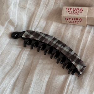 Detailed view of large acetate banana hair clip with classic brown tartan pattern on fabric