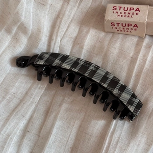 Close-up of black and white checkered banana hair clip on beige textured fabric