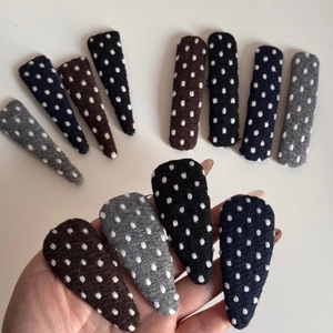 Close-up of knit fabric triangle BB hair clips with white polka dot embroidery details