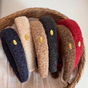 Close-up of soft plush headbands in various colors featuring gold Love metal labels