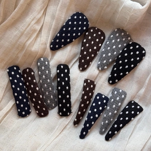 Polka dot fabric hair clips set in navy, coffee, grey, and black colors on textured cloth