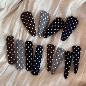 Detailed texture of fabric polka dot hair clips in various shapes and neutral colors