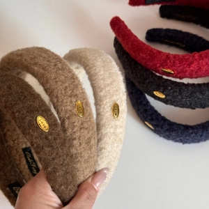 Close-up of plush velvet headbands with gold Love metal plates and thick fabric texture