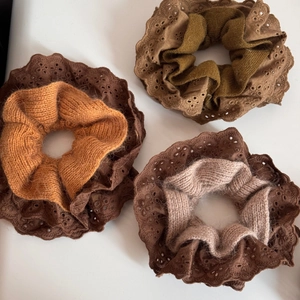 Detail of knitted lace scrunchies in brown, yellow and pink with delicate hollow edges