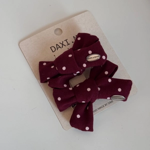 Close-up of wine red polka dot bow hair clips with engraved silver metal MAKE A WISH tags