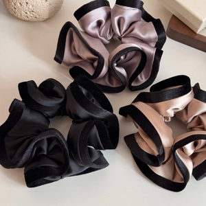 Vue détaillée de chouchous en satin avec bords en velours en noir, violet et champagne