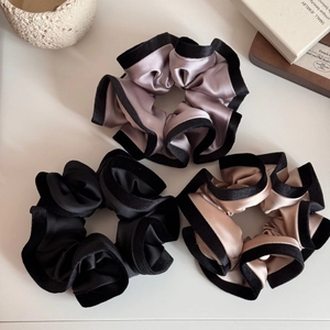 Détail de grands chouchous en satin et velours en rose, noir et couleur champagne