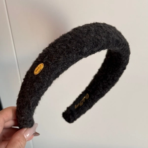 Close-up of black plush headband with golden Love buckle and soft lambskin texture