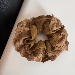 Detail view of double-layered scrunchie with knit fabric and lace embroidery trim