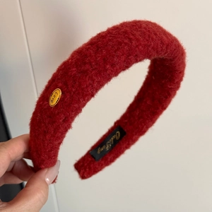 Detail of red plush headband showing soft fleece texture and golden Love metal charm