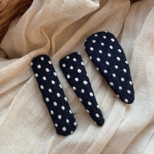 Detailed view of three polka dot fabric hair clips on a natural linen background