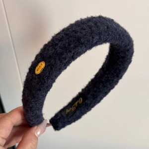 Detail view of navy plush headband showing gold Love tag and soft fuzzy texture