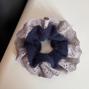 Detailed close-up of double-layered navy wool scrunchie with grey lace floral edge