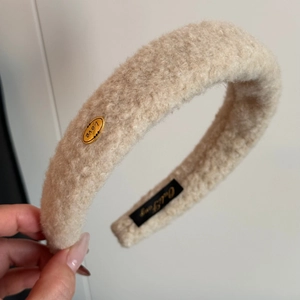 Close-up of beige plush headband with gold Love metal buckle and soft fuzzy texture