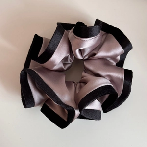 Gros plan sur le chouchou en satin rose avec d'élégants bords à volants en velours noir