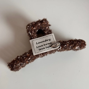 Détail de la pince à cheveux en tweed marron avec textures et pendentif en métal